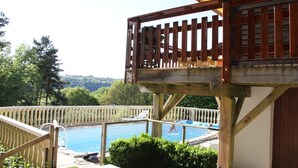A wooden deck with a pool, surrounded by greenery and a clear view of the landscape. - Poolside Bliss Near Lake (Beaulieu)