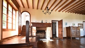 Ein geräumiges Zimmer mit Holzböden, einem Kamin und einer Treppe zu einer weiteren Ebene.