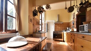 A kitchen with a wooden table, a bench, hanging pots, a stove, and a microwave. - House in Burgundy With Private Pool (Saint-Aubin-sur-Loire)