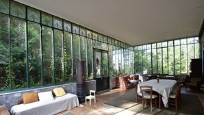 A spacious room with a large window, a sofa, a table with chairs, and a fireplace. - House in Burgundy With Private Pool (Saint-Aubin-sur-Loire)