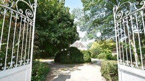A gated entrance with a gravel path leading through a garden. - House in Burgundy With Private Pool (Saint-Aubin-sur-Loire)