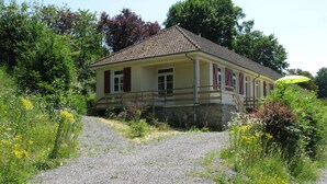 A house with a stone foundation, a wooden deck, and a gravel driveway. - Holiday Home in Luzy With Fenced Garden (Cuzy)