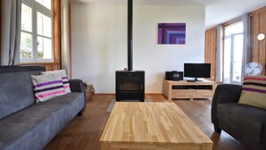 A living room with a wood-burning stove, two sofas, a coffee table, and a television on a wooden stand. - Holiday Home in Luzy With Fenced Garden (Cuzy)