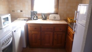 Een kleine keuken met een magnetron, broodrooster, koffiezetapparaat en een koelkast.