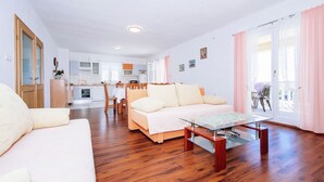 A spacious living area with a sofa, a glass coffee table, and a dining table with chairs. A kitchen is visible in the background, and there is a sliding glass door leading to an outdoor area. - Spacious Holiday Home With Private Pool (Polaca)