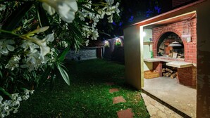An outdoor brick oven with a stone wall and a grassy area with stepping stones. - Spacious Holiday Home With Private Pool (Polaca)
