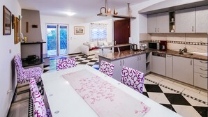 Ett kompakt bostadsutrymme med matplats, kök och balkong.