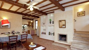A spacious living area with a fireplace, a dining table set for a meal, and a cozy seating area with a patterned rug. - Cottage in Tuscany With Pool & Olive Groves (Lucignano)