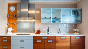 Eine moderne Küche mit einer Edelstahl-Dunstabzugshaube, Holzschränken und einem einbauartigen Schrank mit Glastür über der Spüle.