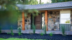 A stone house with a wooden door and window, surrounded by a landscaped garden. - Niagara Wine Routes Fifth street (St. Catharines)