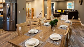 A dining area with a wooden table set for six, surrounded by wooden chairs. A stainless steel refrigerator is visible in the background. - Niagara Wine Routes Fifth street (St. Catharines)