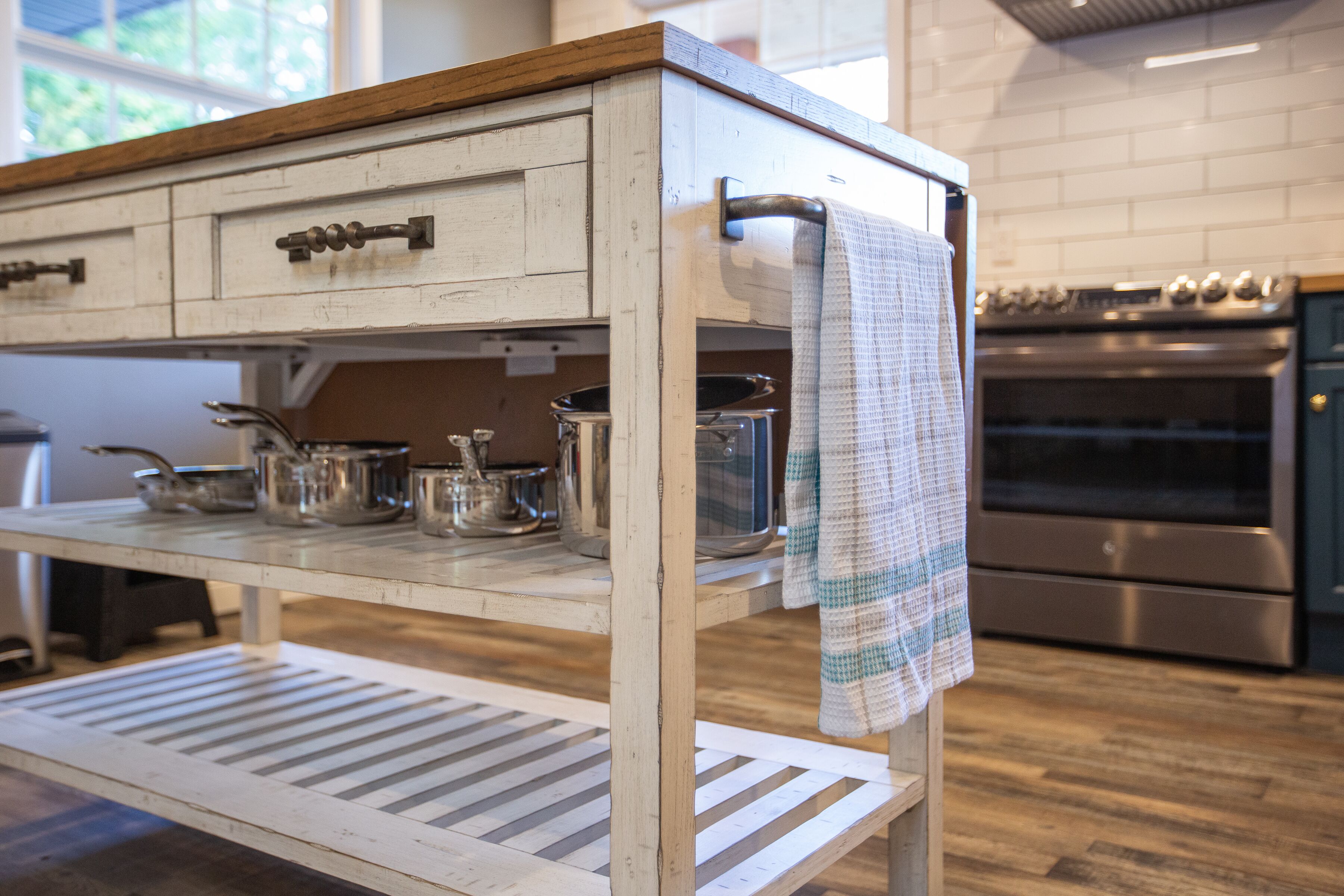 A kitchen with a wooden countertop, stainless steel pots, a hanging towel, and a modern oven.