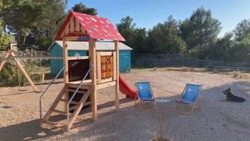 Children can play and relax in this outdoor play area featuring a playhouse with a slide.