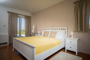 Un dormitorio con cama, mesitas de noche, una ventana con cortinas y vistas al exterior.