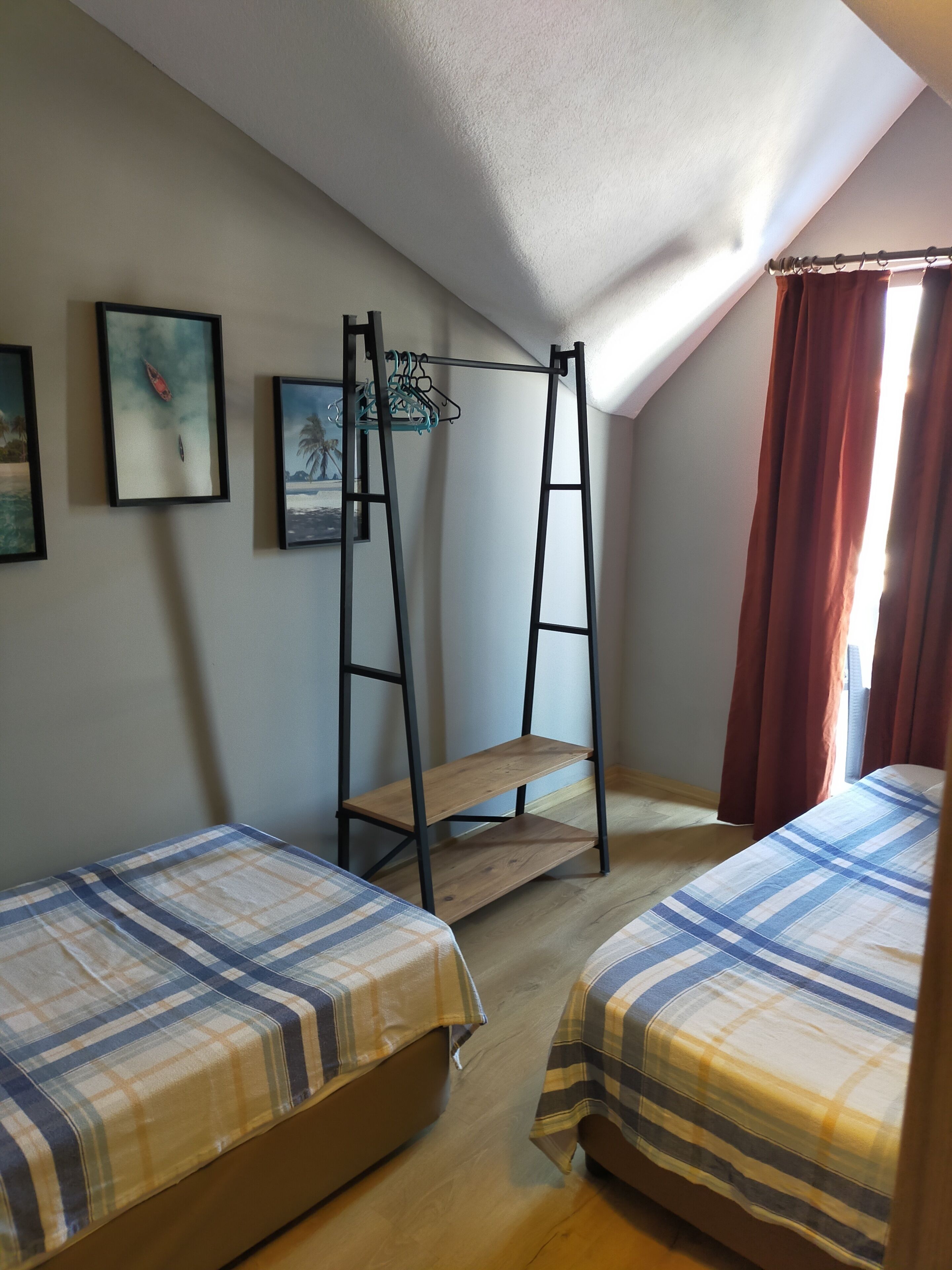 A dormitory room with two beds, a wooden ladder, and two framed pictures on the wall.