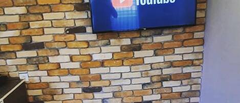 A YouTube logo on a flat-screen TV mounted on a brick wall.