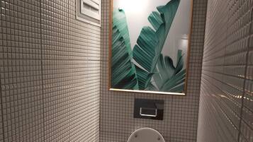 Ein Badezimmer mit gefliestem Boden, einer Toilette, einem Mülleimer und einem gerahmten Bild an der Wand.