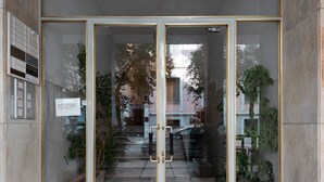 Een gebouwde ingang met glazen deuren, een trap en plantenbakken.