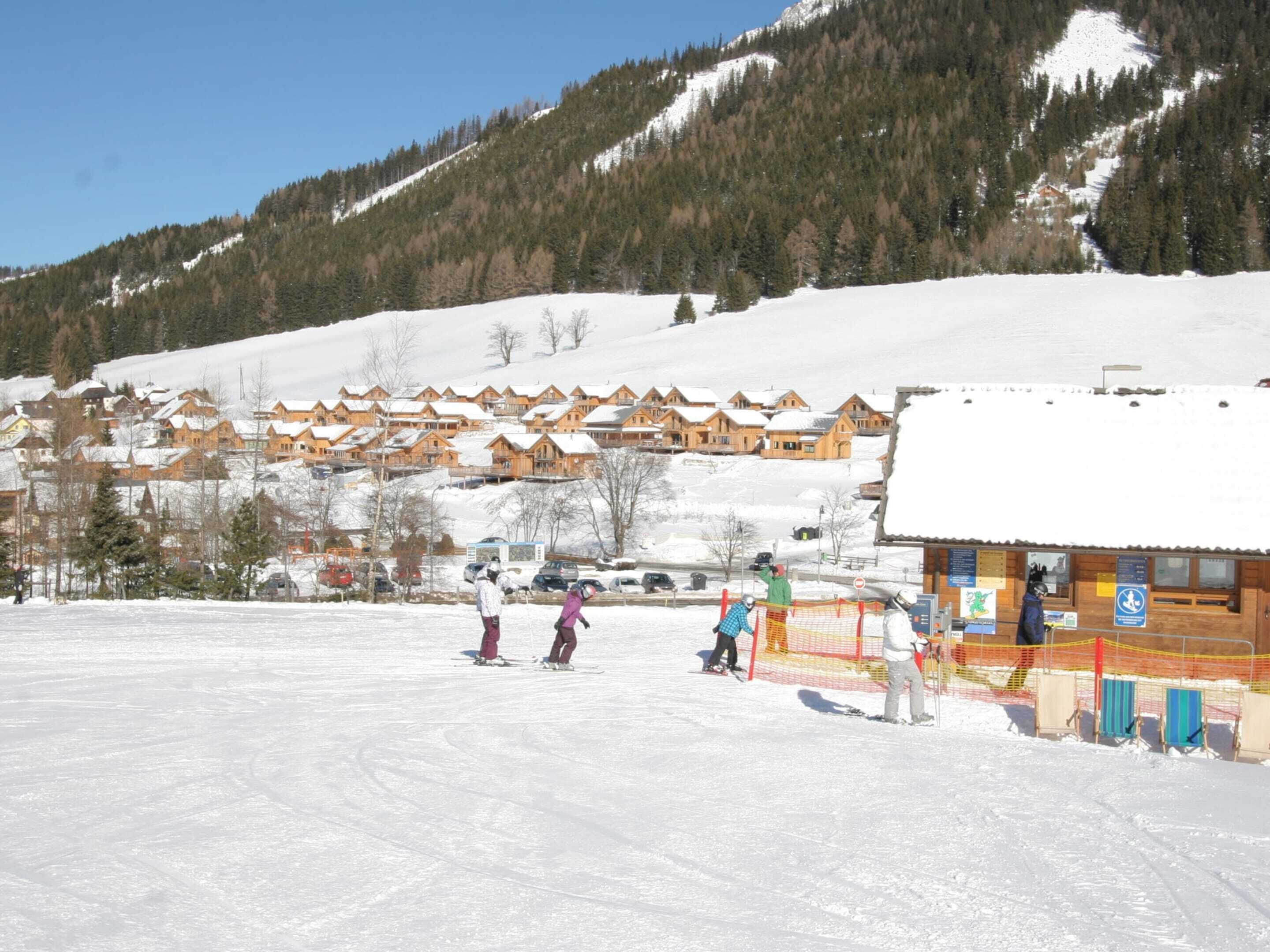 A snow-covered ski resort with wooden cabins and a ski lift.