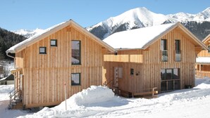 A wooden chalet with a snow-covered roof, set against a backdrop of snow-capped mountains. - Chalet in Hohentauern Near Ski Lift (Hohentauern)