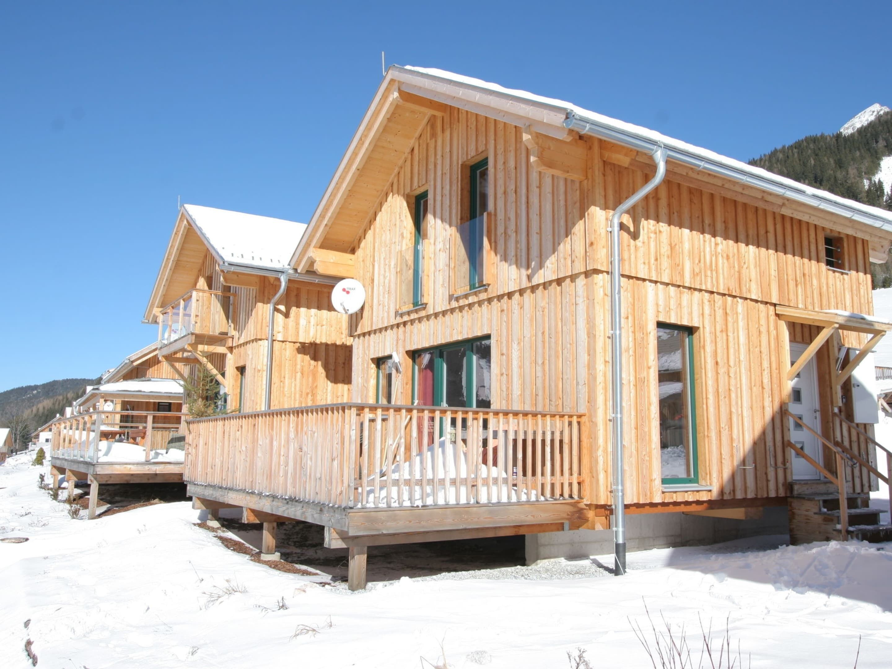 Eine Holzhütte mit Balkon und überdachter Veranda, umgeben von Schnee.