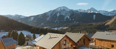 A wooden cabin complex with a view of snow-capped mountains.