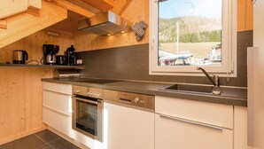 A modern kitchen with wooden beams, a built-in oven, a stainless steel range, and a window overlooking a scenic outdoor area. - Chalet in Hohentauern Near Ski Lift (Hohentauern)