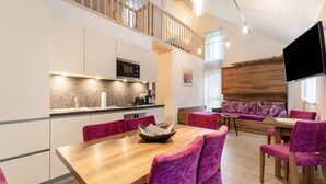 A modern kitchen with a dining area featuring a wooden table and purple upholstered chairs.
