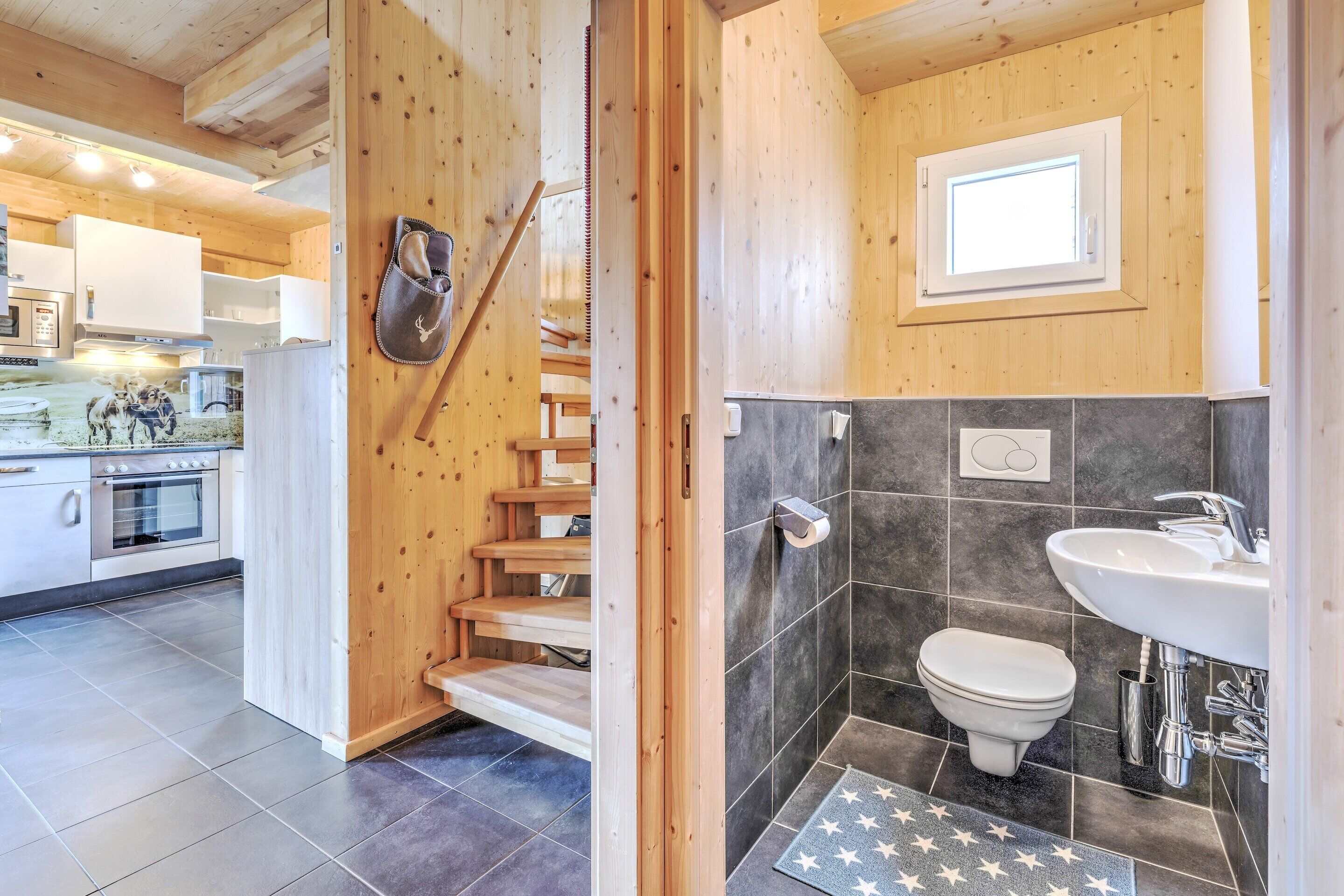 A wooden interior with a kitchen, a bathroom with a toilet, and a star-patterned mat.