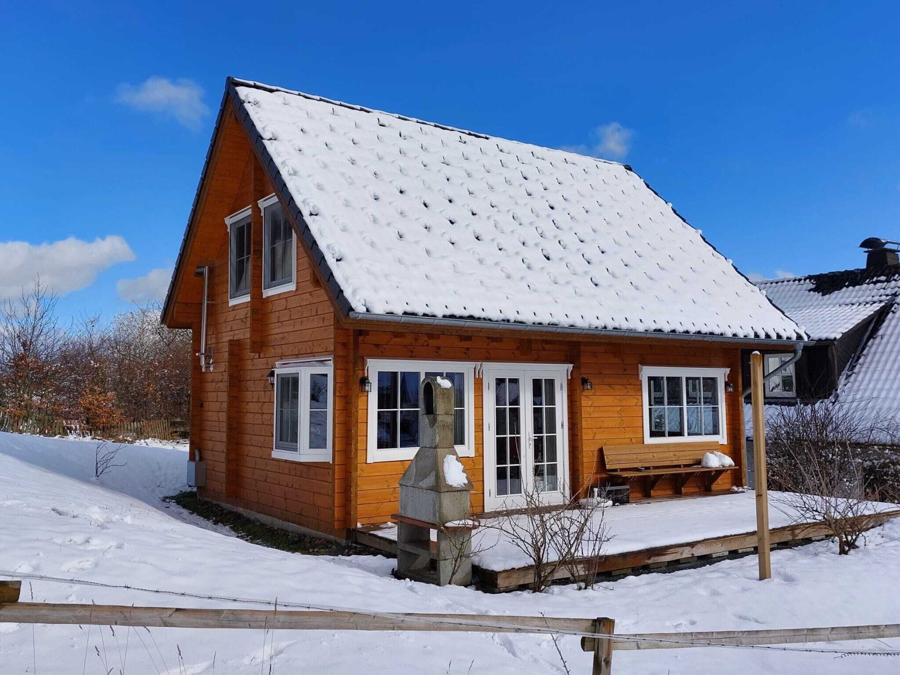 Ein Holzhaus mit verschneitem Dach und einer Veranda.
