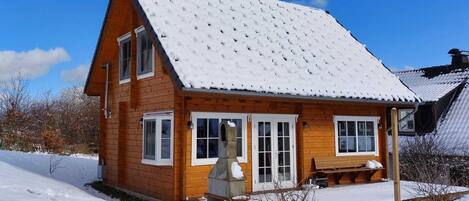 Ein Holzhaus mit verschneitem Dach und einer Veranda.