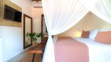 A bedroom with a bed, a bedside table, a mirror, and a TV mounted on the wall.