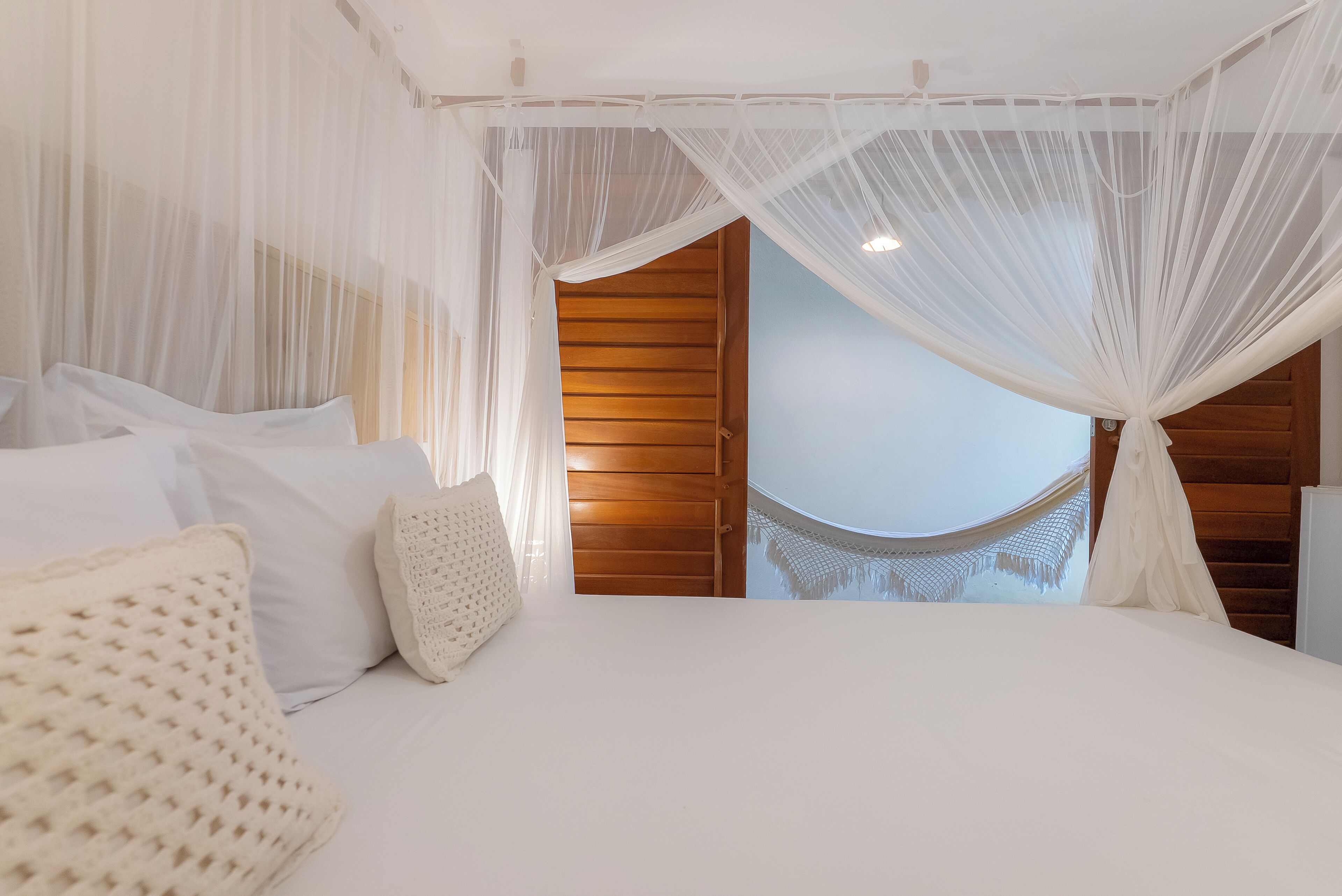 A bedroom with a canopy bed, wooden paneling, and a view of a wooden staircase.