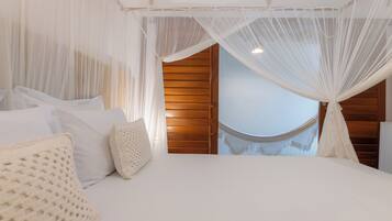 A bedroom with a canopy bed, wooden paneling, and a view of a wooden staircase.