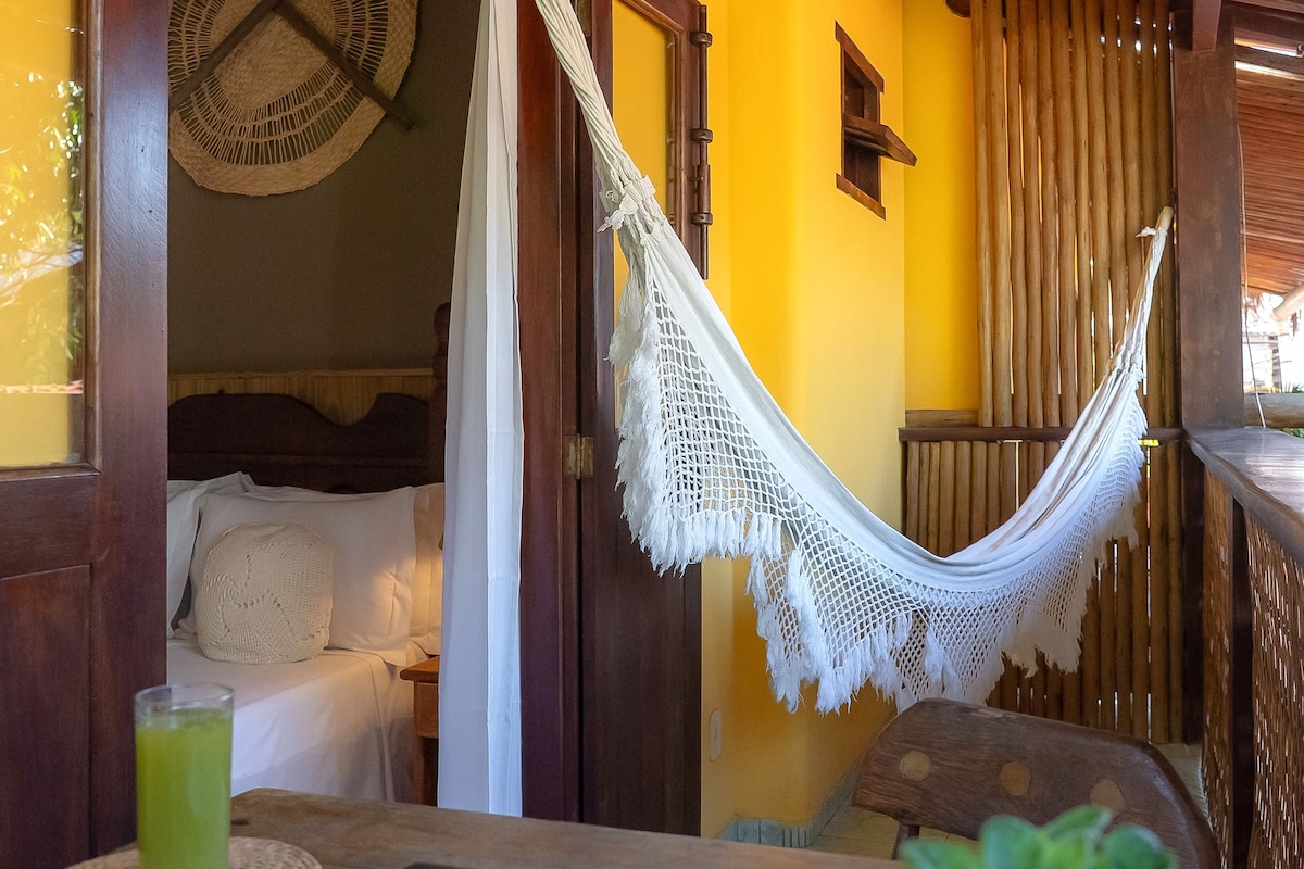A room with a hammock, a bed, a laptop, and a potted plant.