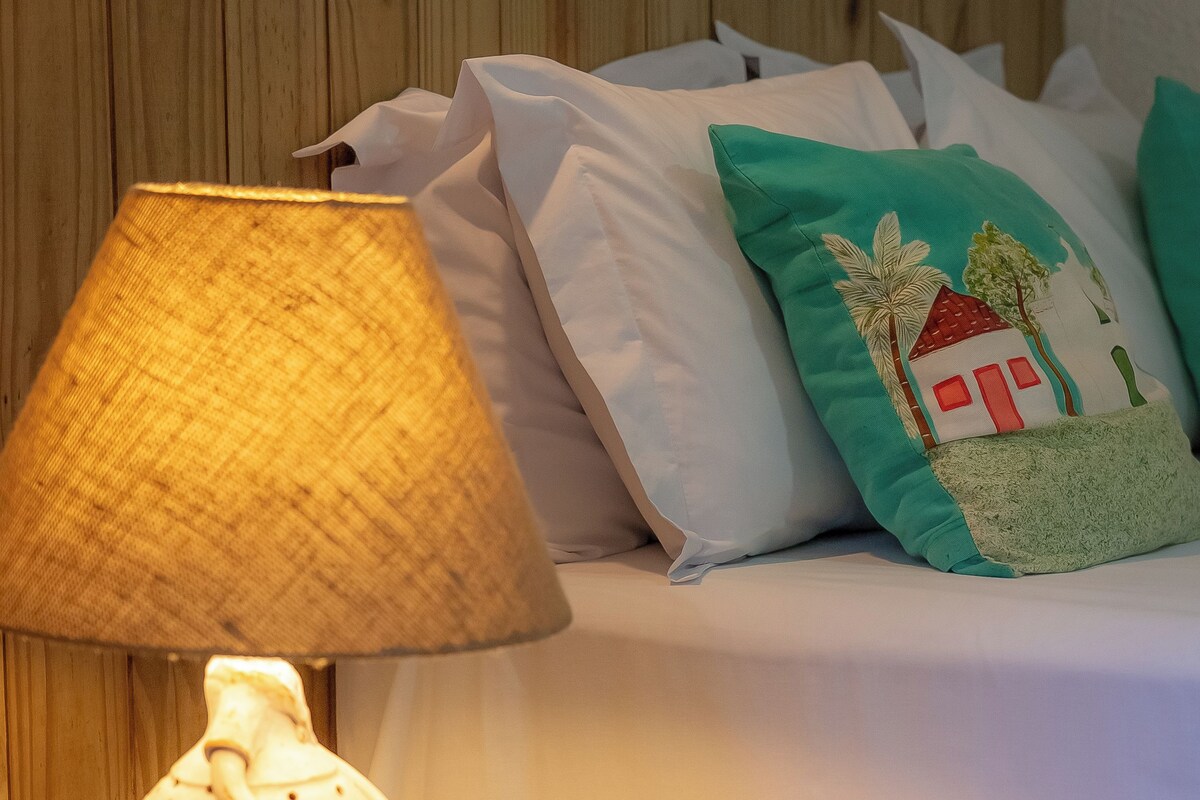A wooden bedside table with a lamp and a tissue holder.