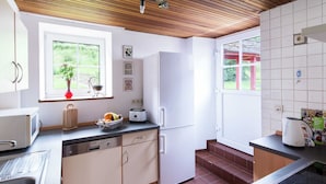 Une cuisine moderne avec un plafond en bois, des armoires blanches, une fenêtre avec vue, un évier et un grille-pain.