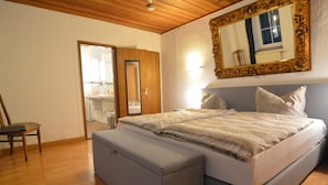 Une chambre Ă coucher avec un lit, une chaise, un miroir et un plafond en bois.