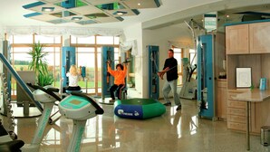 A gym with exercise equipment, a treadmill, and a person using a resistance machine. - Geraumige Ferienwohnung in Stocking in Waldnahe (Waldkirchen)