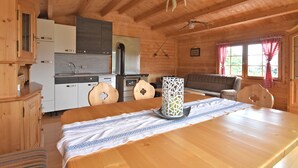 A wooden cabin interior with a kitchen, dining area, and a sofa. - Geraumige Ferienwohnung in Stocking in Waldnahe (Waldkirchen)