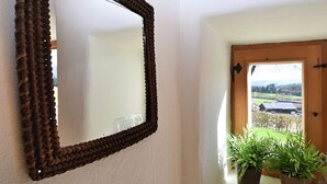 A hallway with a woven mirror on the wall, a wooden door leading outside, and two potted plants on the floor. - Holiday Home in Konzell With Terrace (Konzell)