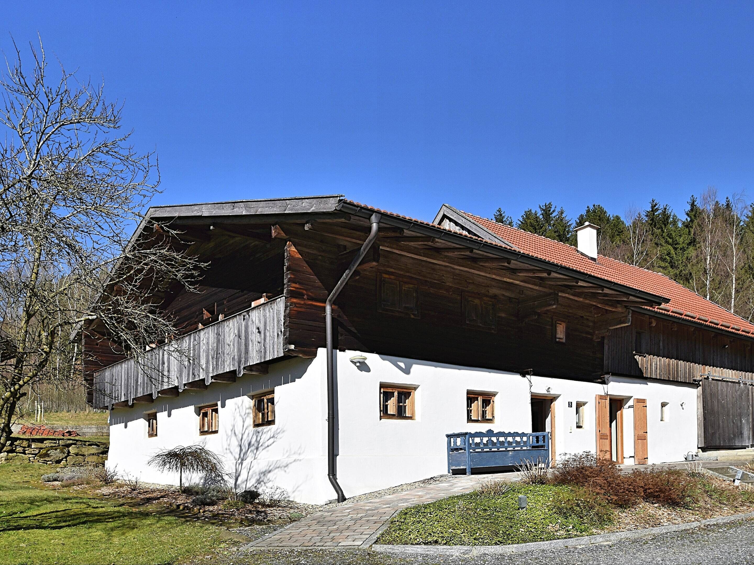 A rustic building with a sloped roof and wooden exterior, featuring a bench and a small garden area in front.