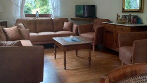 A living room with a brown sofa set, a wooden coffee table, and a television on a stand. - Hellenthal Family Retreat (Hellenthal)