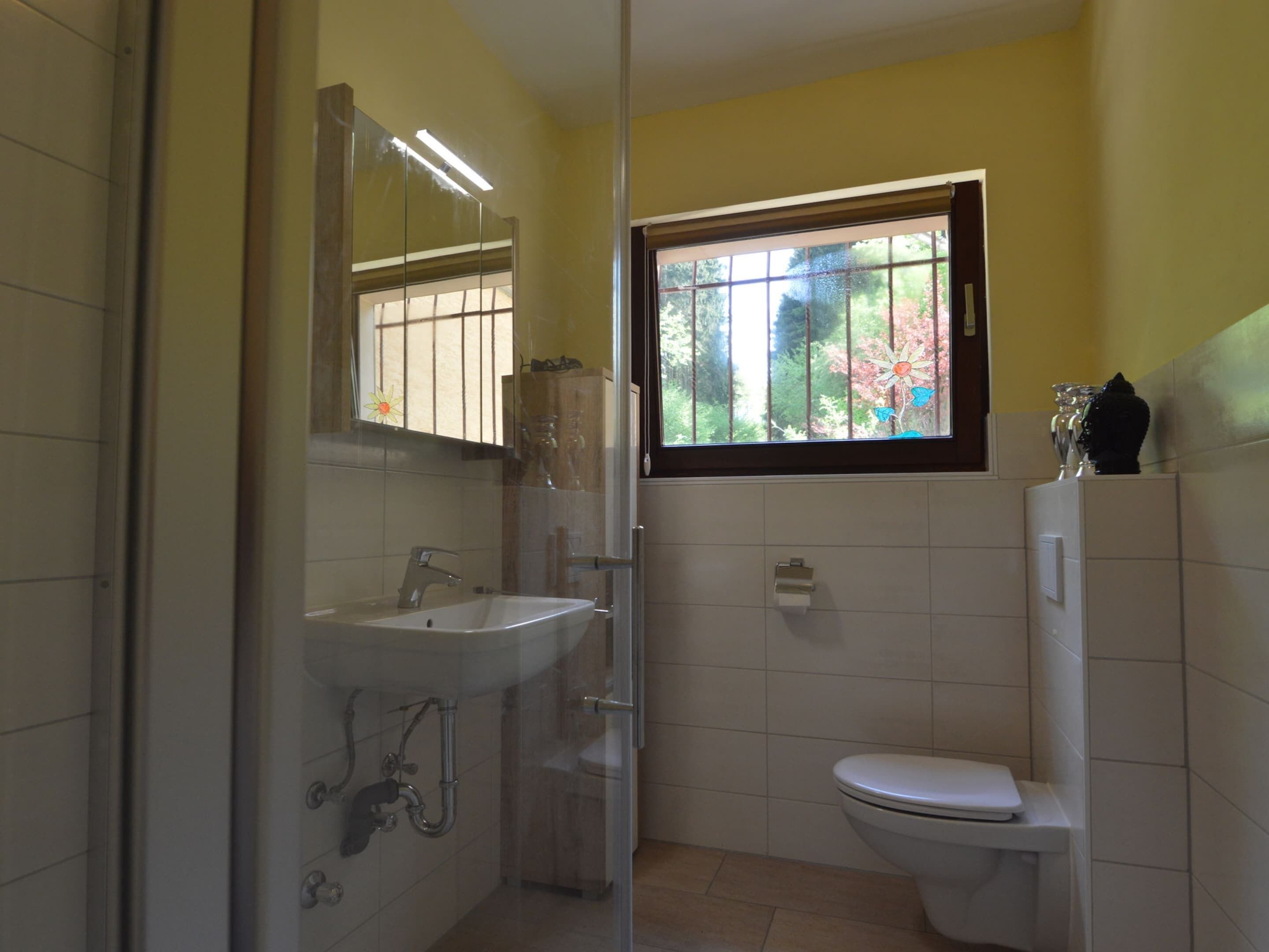A small bathroom with a sink, toilet, and window.