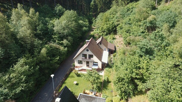 A house surrounded by dense forest, with a visible driveway and a small garden area. - Hellenthal Family Retreat (Hellenthal)