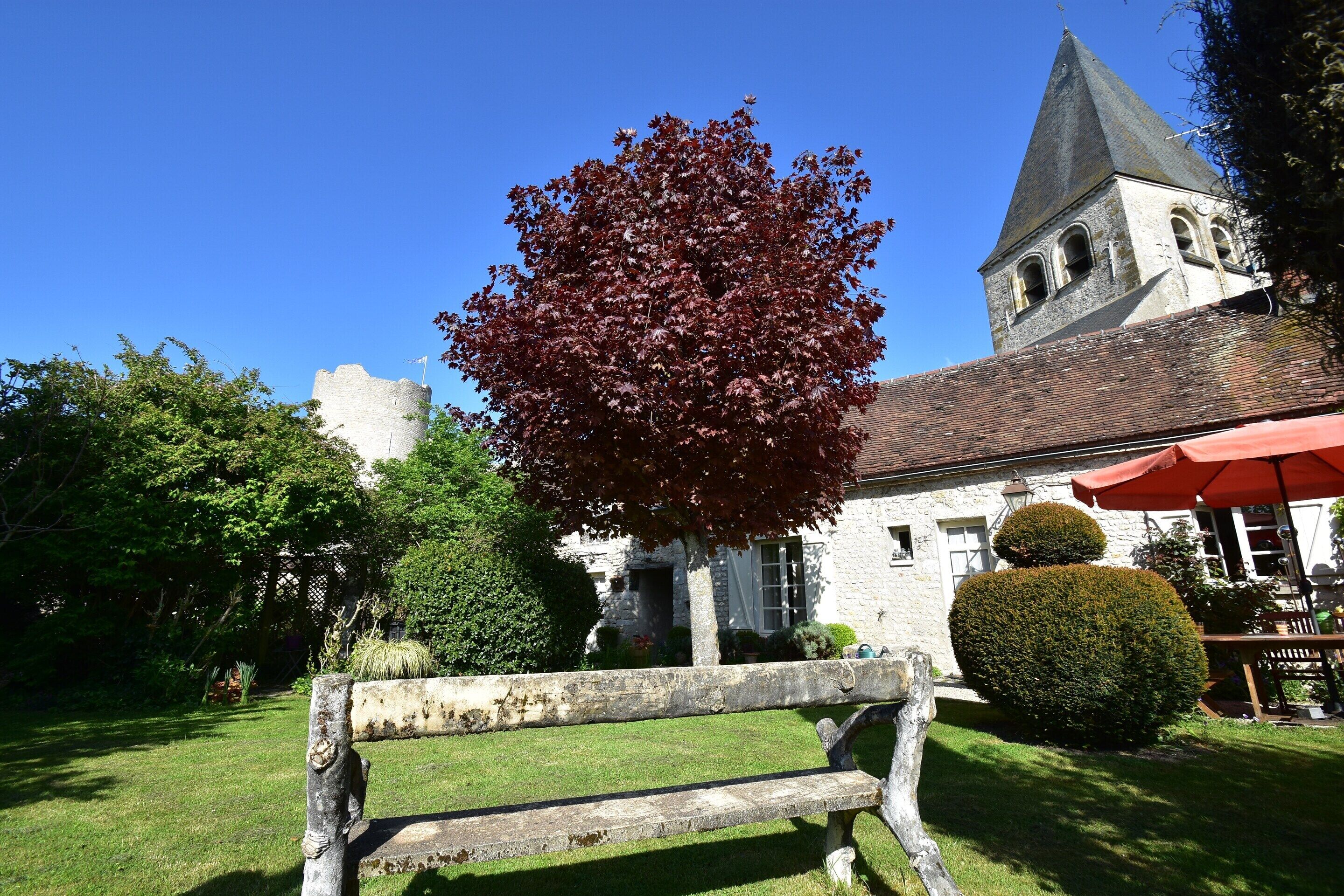 A stone building with a tower, a bench, and a well-maintained garden.