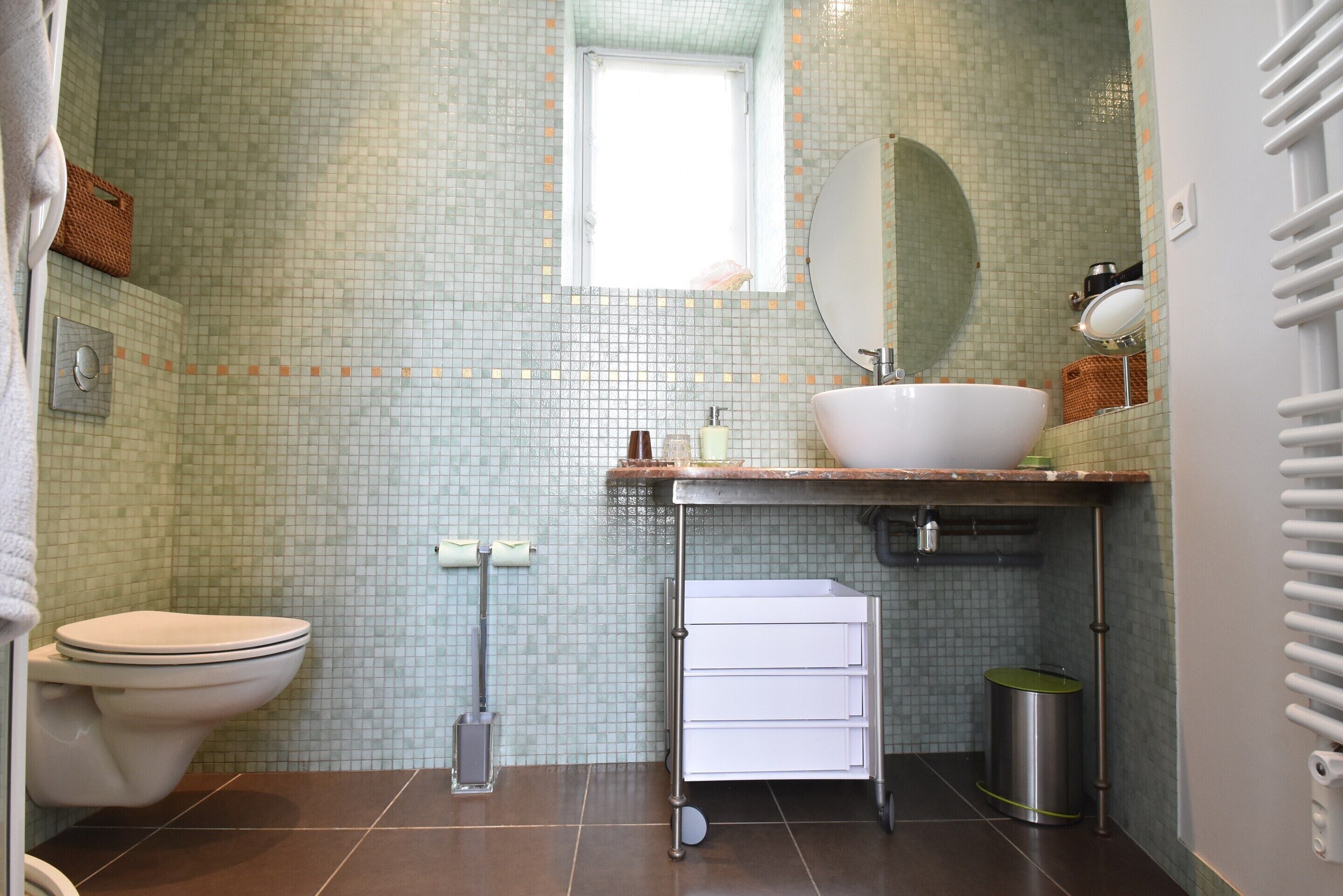 Ein Badezimmer mit Toilette, Waschbecken, Spiegel und gefliesten Wänden.