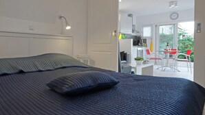 A bedroom with a large bed, a bedside lamp, and a view of a kitchen and dining area through an open door. - Beautiful Holiday Home Near Lawn Bowling in Krabbendam (Warmenhuizen)