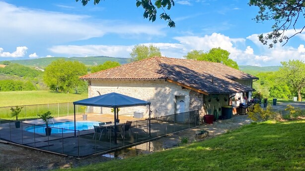 Une maison en pierre avec une piscine, un espace salon extérieur et une vue sur la campagne.