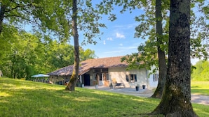 Une maison avec un toit en tuiles, une terrasse et une pelouse.